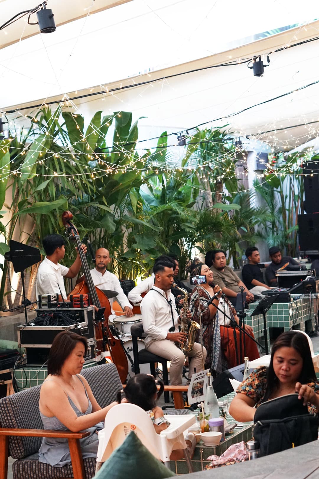 A band playing on Luma's planted terrace under strung lights, guests seated around them