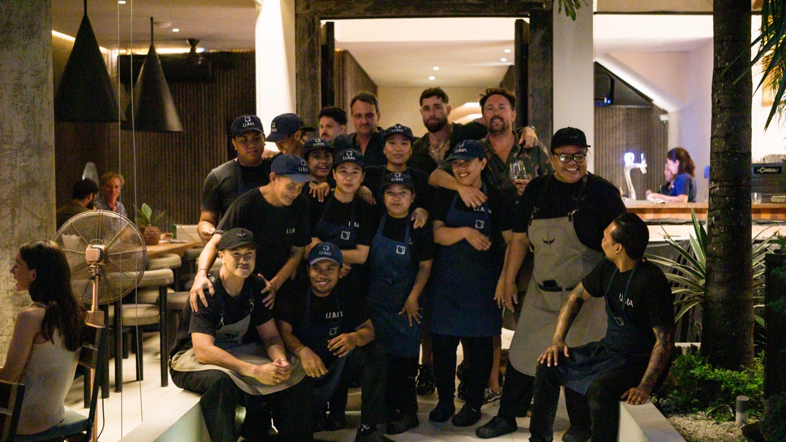 Luma's full team together in the dining room at night, kitchen and floor staff in LUMA caps and aprons